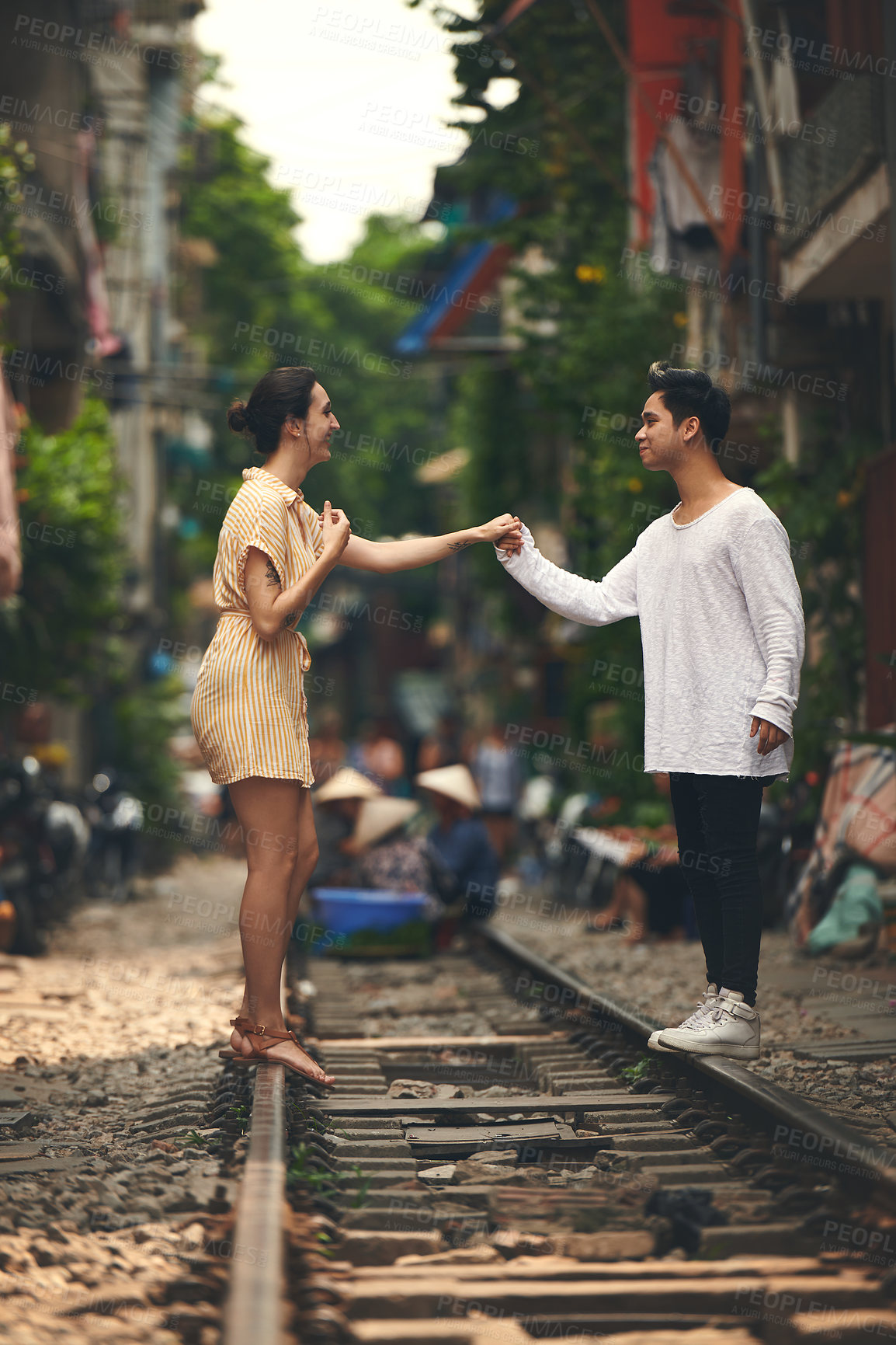 Buy stock photo Travel, holding hands and couple on train tracks in Vietnam for holiday, vacation and tourist destination. Happy, love and man and woman on railway for adventure, journey and bonding in urban city