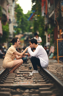 Buy stock photo Shot of a young couple sharing a romantic moment on the train tracks in the streets of Vietnam