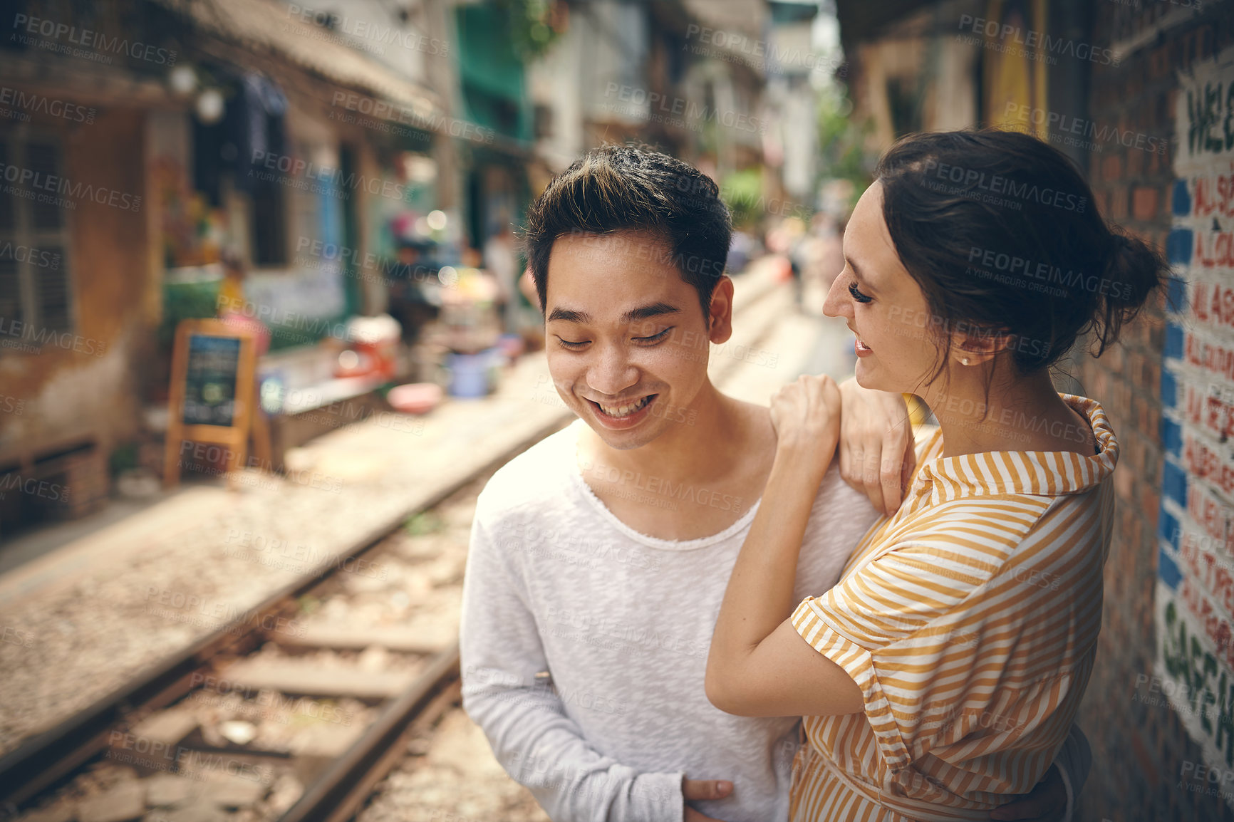 Buy stock photo City, railway and couple with love on vacation, travel adventure and exploring for anniversary. Interracial marriage, woman and man with smile for admiration, loyalty and bonding outdoor in Vietnam