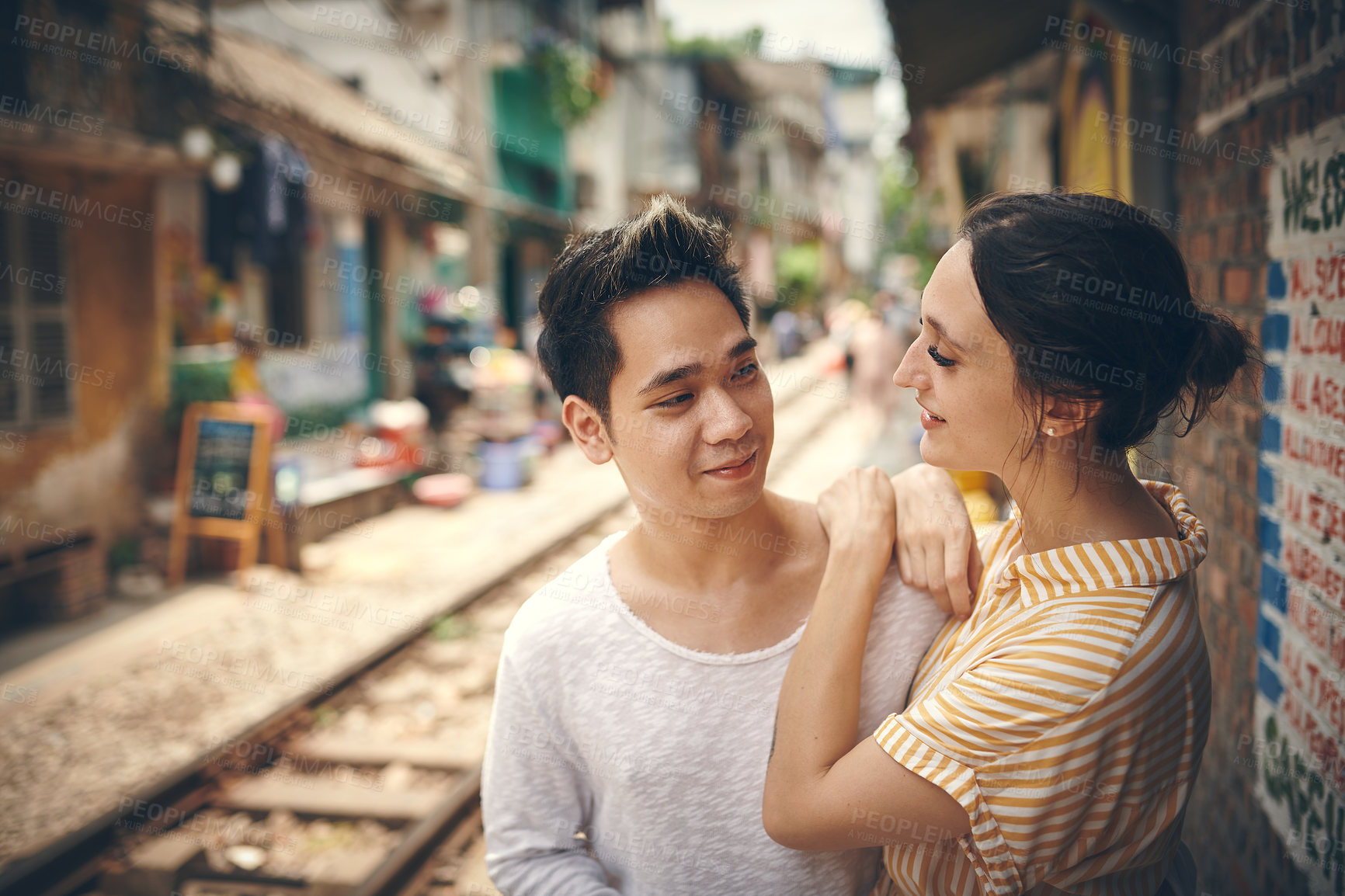 Buy stock photo City, railway and couple with love for adventure, travel vacation and exploring for anniversary. Interracial marriage, woman and man with smile for admiration, loyalty and bonding outdoor in Vietnam