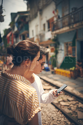 Buy stock photo Shot of a young couple using a smartphone while waiting for their train to arrive in Vietnam