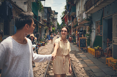 Buy stock photo Travel, walking and couple holding hands on train tracks for holiday, romance and outdoor date together. Love, man and woman in street market with fun, weekend adventure and happy vacation in Vietnam