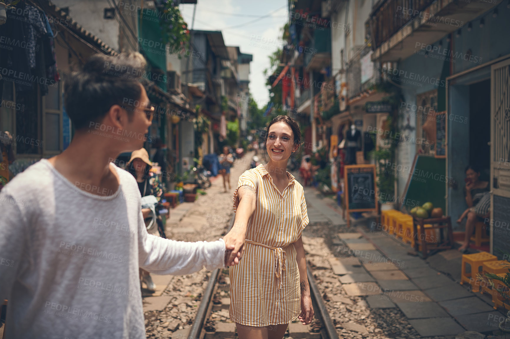 Buy stock photo Travel, walking and couple holding hands on train tracks for holiday, romance and outdoor date together. Love, man and woman in street market with fun, weekend adventure and happy vacation in Vietnam