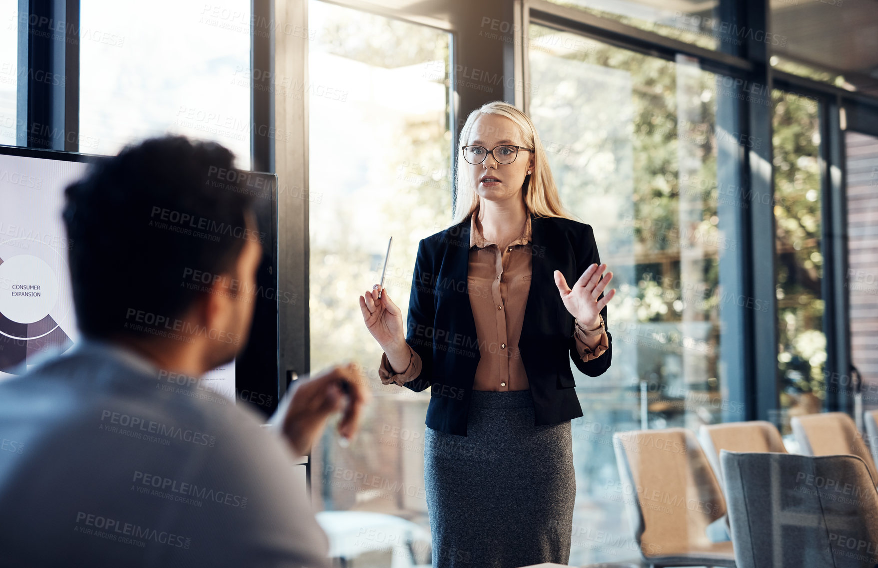 Buy stock photo Shot of a young businesswoman delivering a presentation to her colleague in the boardroom of a modern office