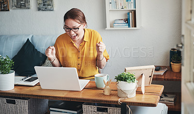 Buy stock photo Cropped shot of an attractive young businesswoman sitting alone in her home office and feeling excited while using her laptop