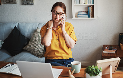 Buy stock photo Cropped shot of an attractive young businesswoman sitting alone in her home office and feeling stressed while using her cellphone