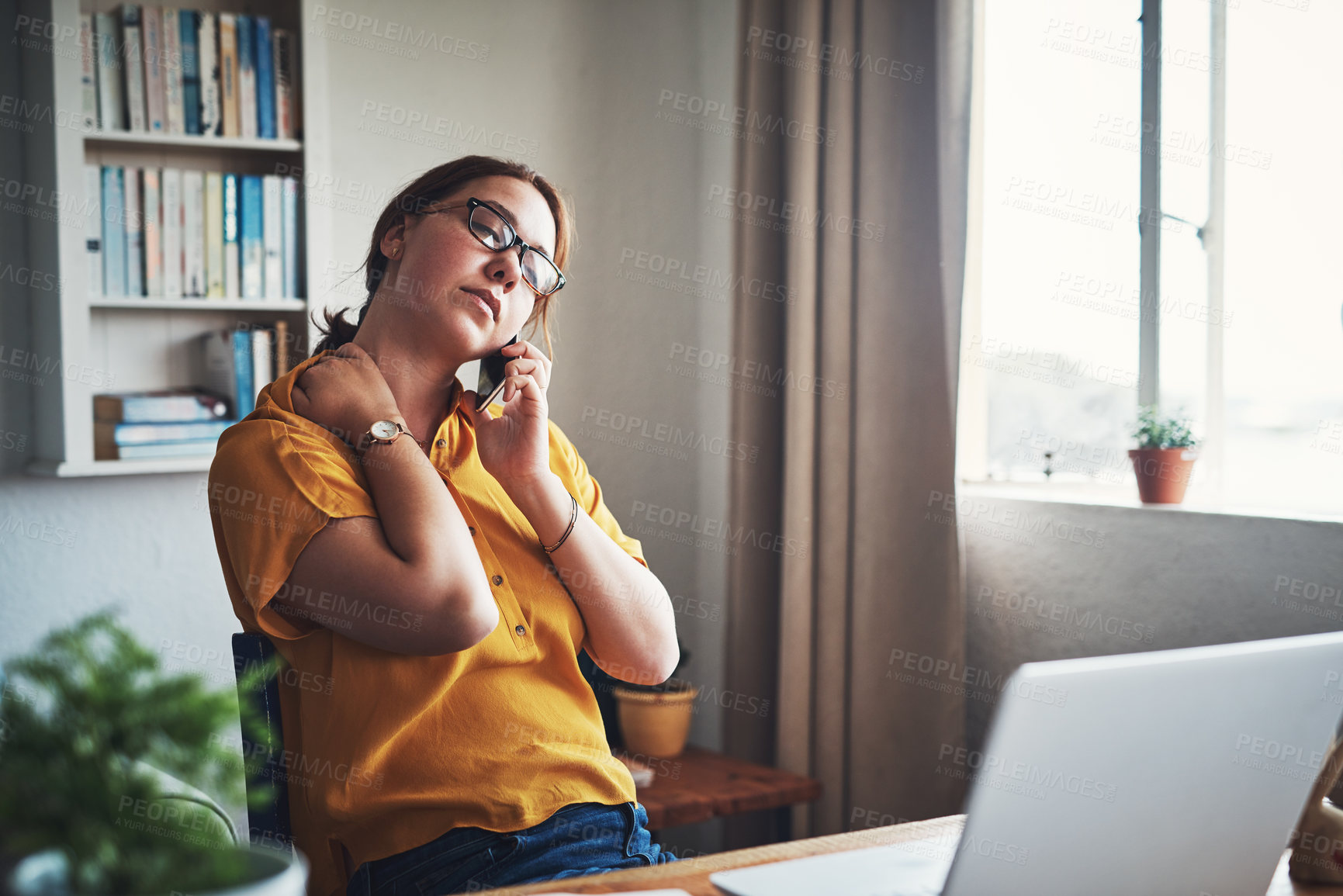 Buy stock photo Cropped shot of an attractive young businesswoman sitting alone in her home office and feeling stressed while using her cellphone
