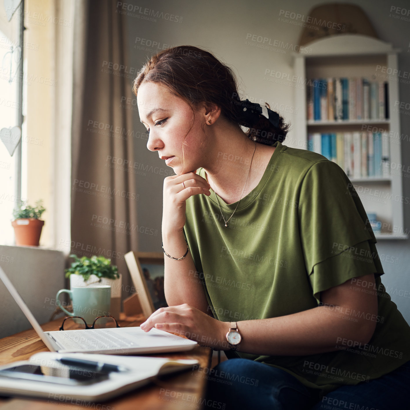 Buy stock photo Cropped shot of an attractive young businesswoman sitting alone in her home office and looking contemplative while using her laptop