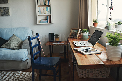 Buy stock photo Cropped shot of technology and a notebook on a desk in an empty home office during the day