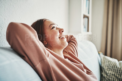 Buy stock photo Cropped shot of an attractive young woman sitting alone in her living room with her hands behind her head