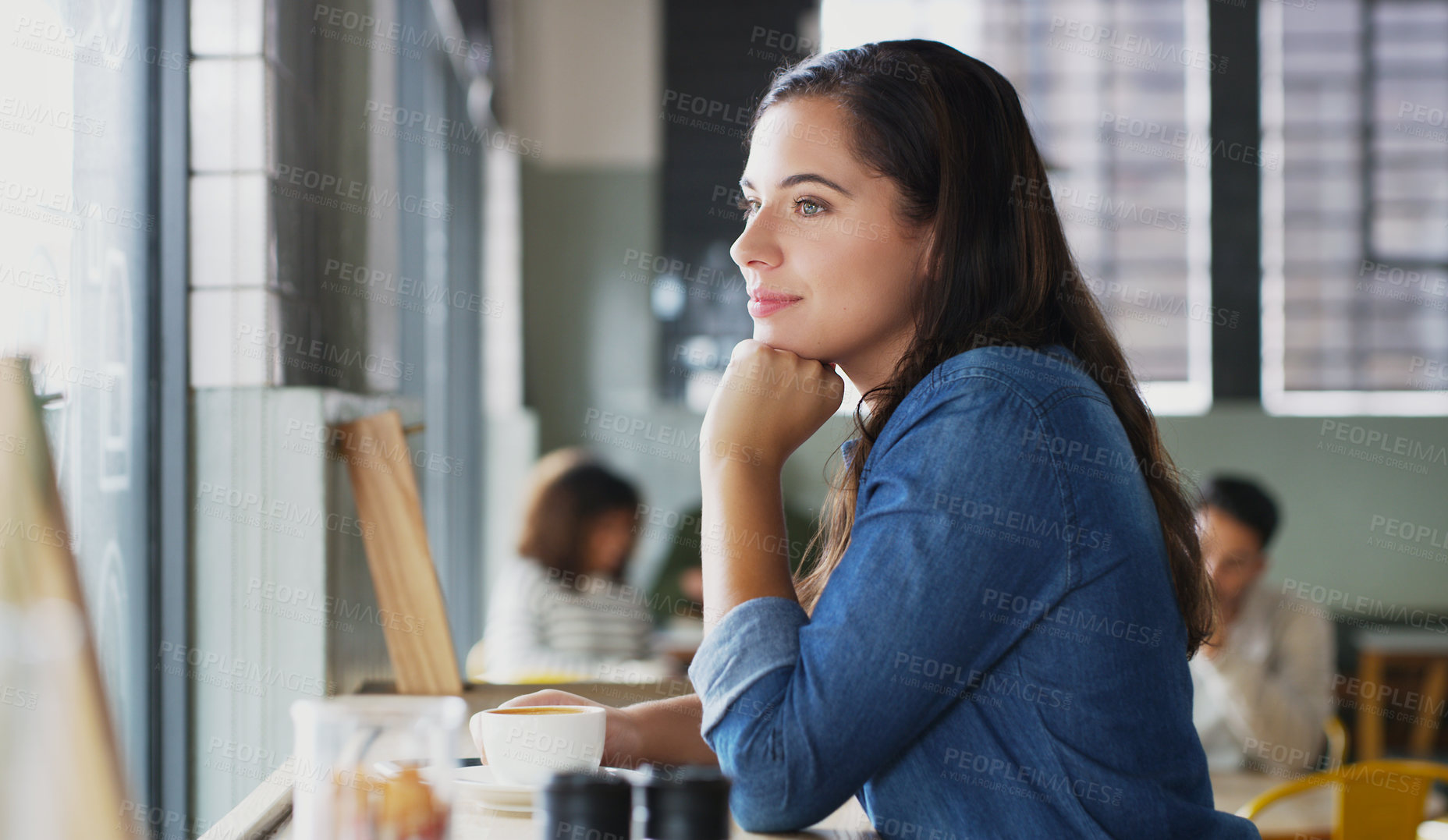 Buy stock photo Shot of an attractive young woman looking thoughtful in a cafe