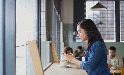 Buy stock photo Shot of an attractive young woman using a cellphone in a cafe