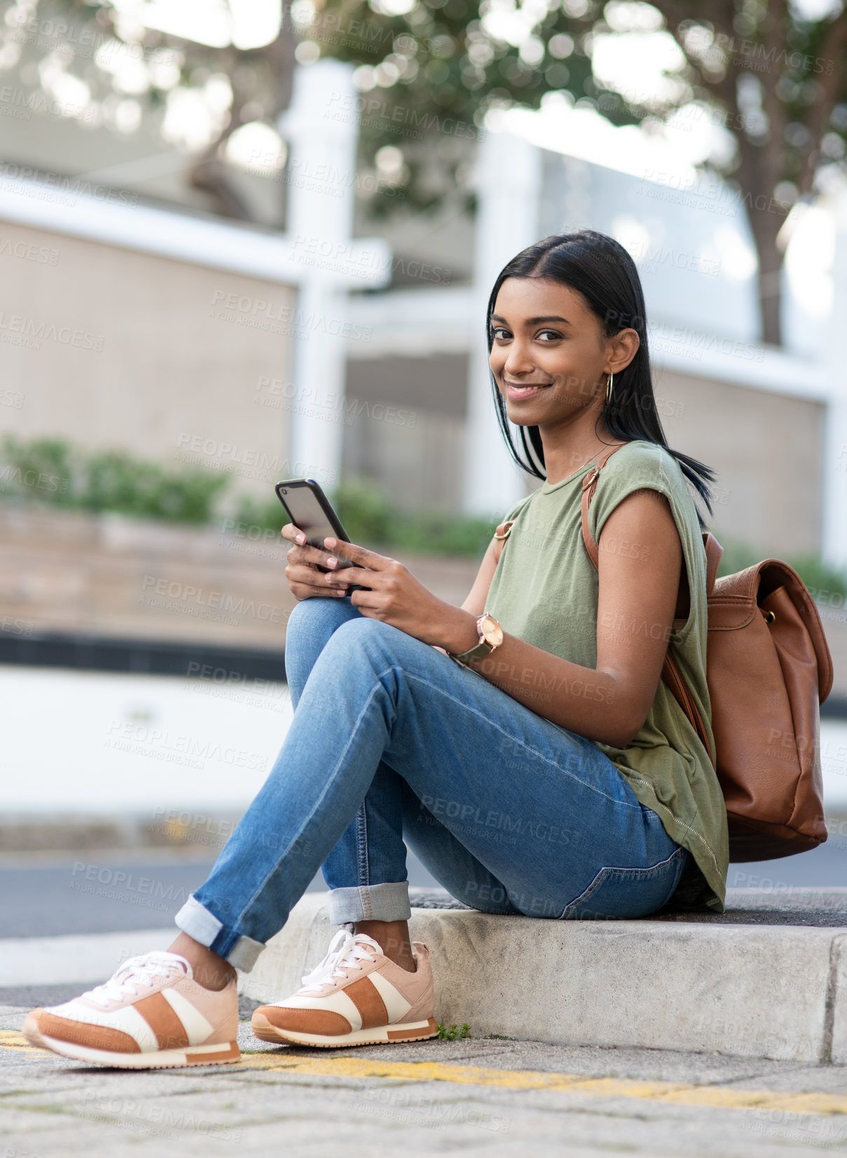 Buy stock photo Full length portrait of an attractive young woman using a smartphone while sitting in the city
