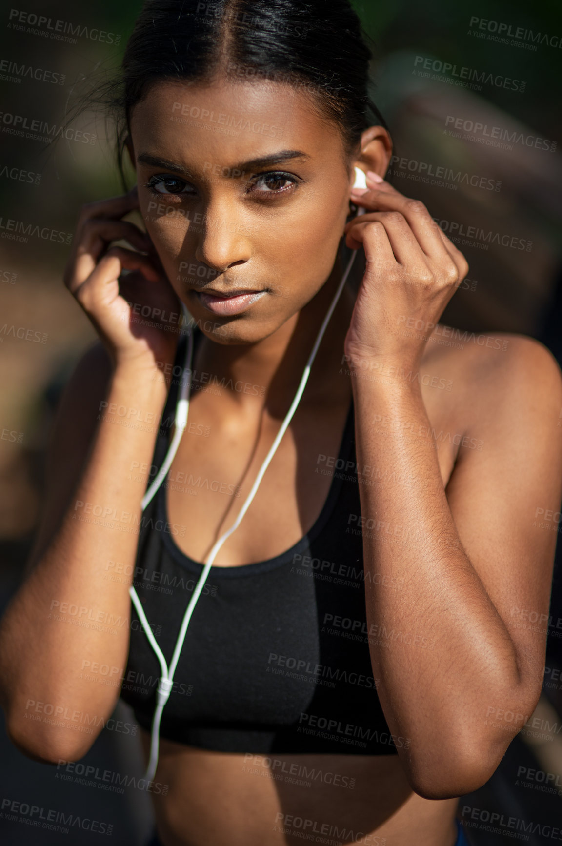 Buy stock photo Portrait of a sporty young woman listening to music while exercising outdoors
