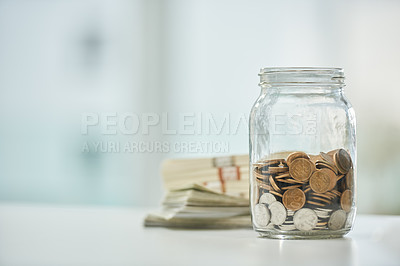 Buy stock photo Full length shot of a jar of coins and wads of cash on a desk in an office