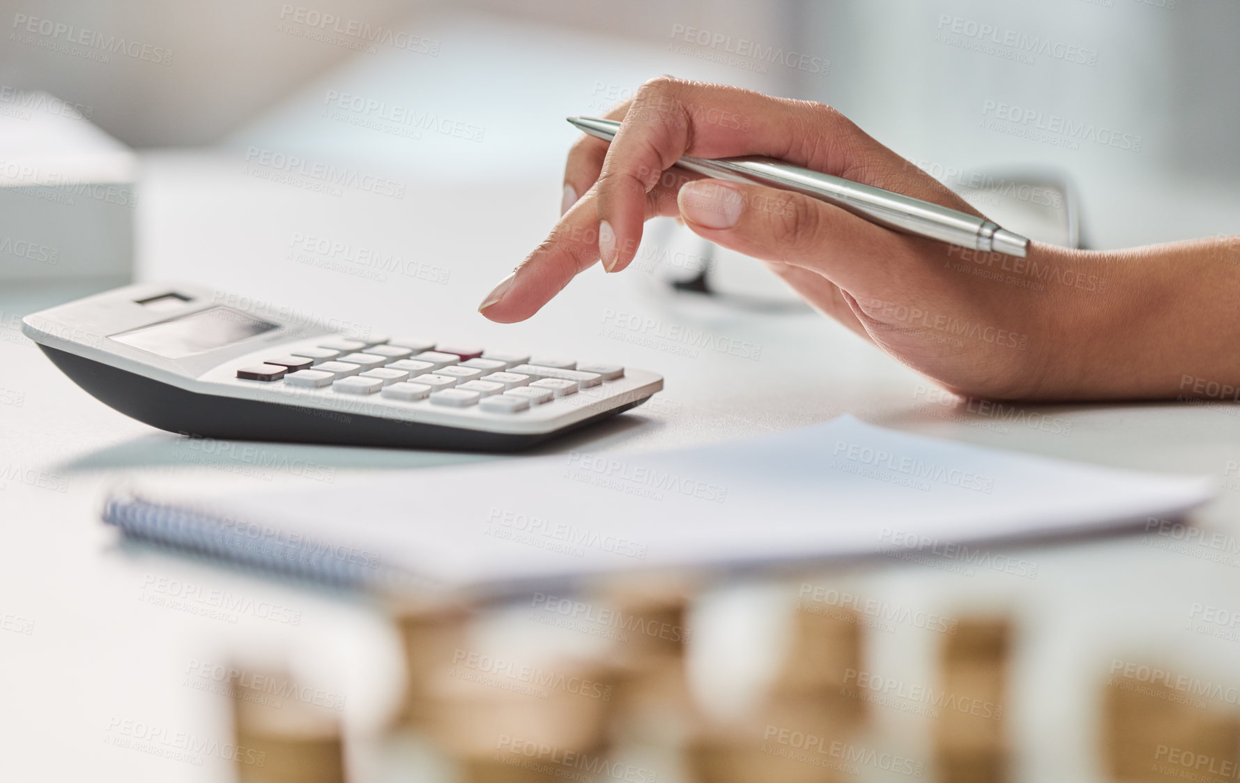 Buy stock photo Cropped shot of an unrecognizable businesswoman working out her finances with a calculator and a notepad in her office