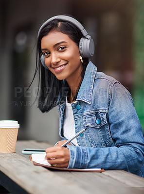 Buy stock photo Happy woman, portrait and student writing with headphones for audio, learning or music at outdoor cafe. Young female person or Indian with smile, listening to online podcast and taking notes in book
