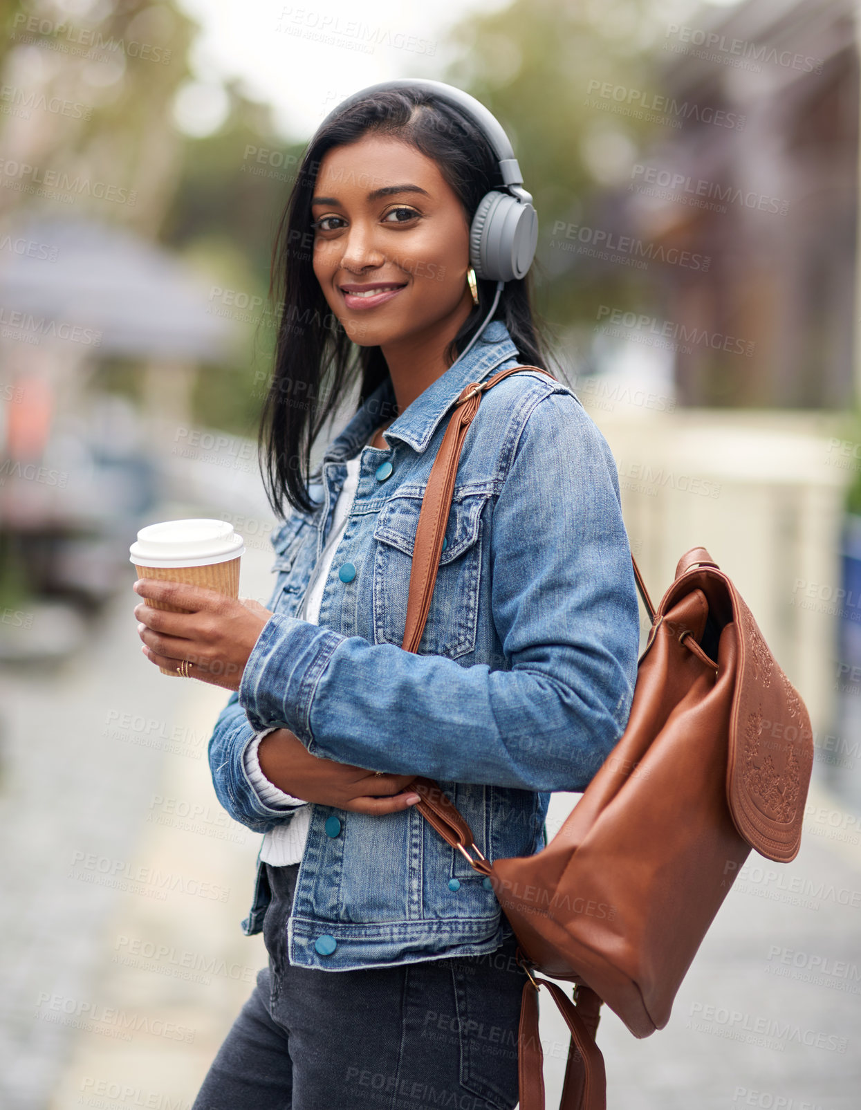 Buy stock photo Shot of a woman wearing headphones and holding a takeaway coffee outdoors