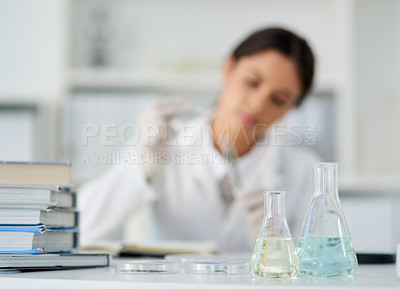 Buy stock photo Shot of beakers in a lab with a young scientist working in the background