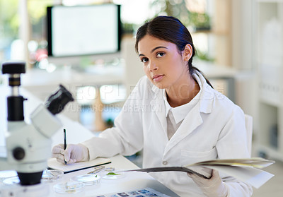 Buy stock photo Portrait of a young scientist writing notes while working in a lab