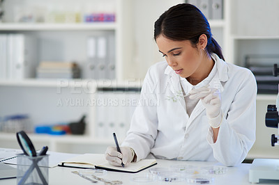 Buy stock photo Shot of a young scientist writing notes while analysing samples in a lab