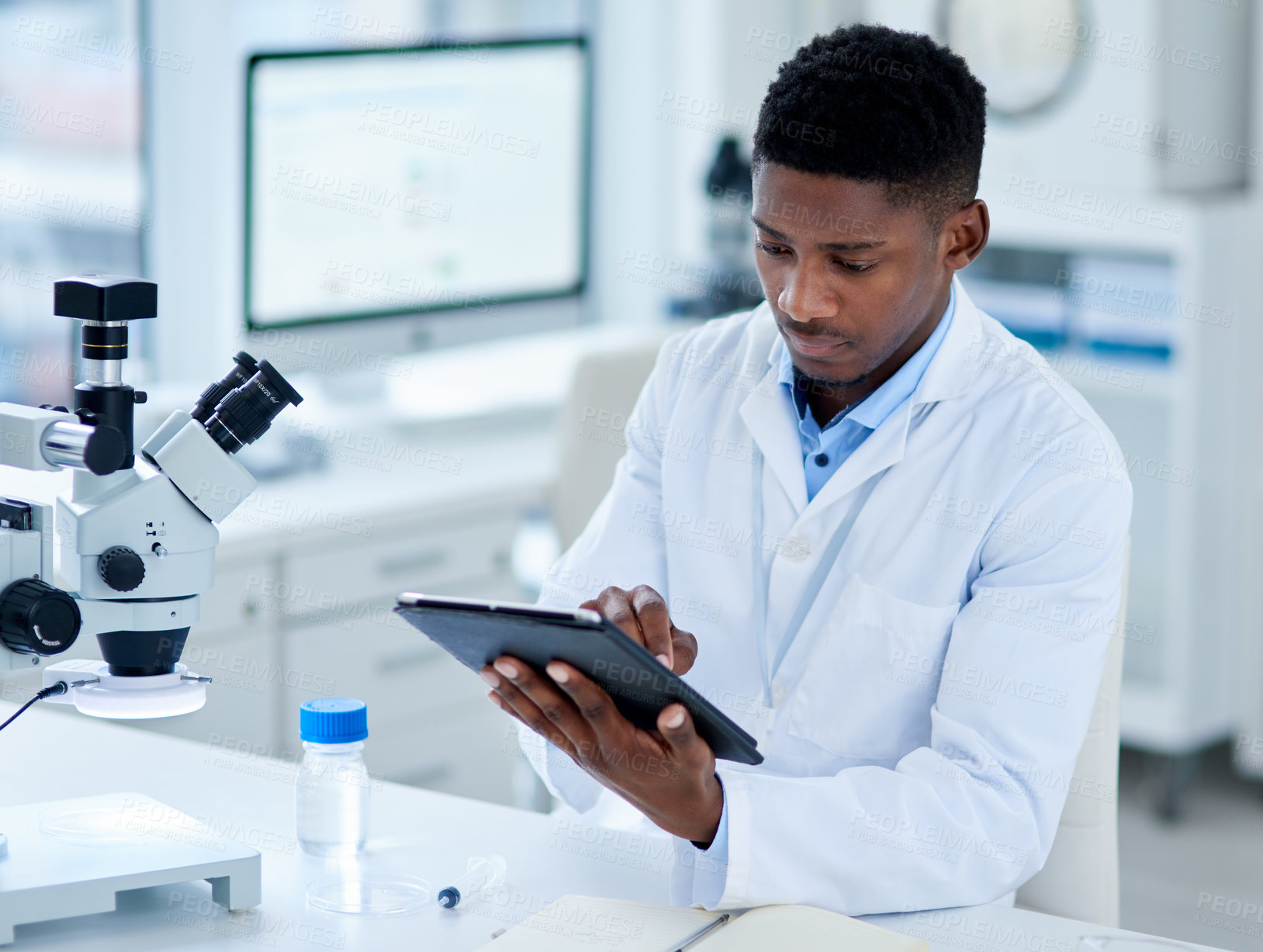 Buy stock photo Cropped shot of a focused young male scientist browsing on a digital tablet inside of a laboratory during the day
