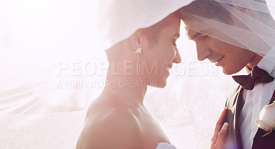Buy stock photo Cropped shot of an affectionate young newlywed couple sharing an intimate moment while covering themselves with a veil on their wedding day