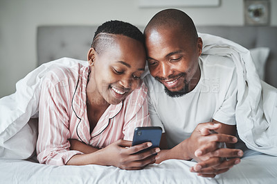 Buy stock photo Phone, social media and morning with a black couple in bed together to relax in the bedroom of their home. Mobile, meme or contact with a man and woman browsing the internet while relaxing or bonding