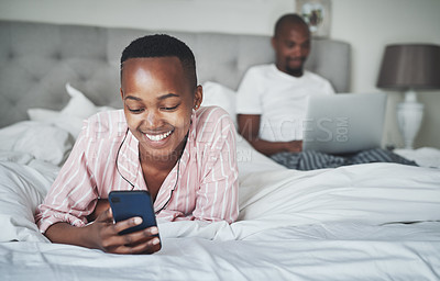 Buy stock photo Black woman with smartphone, relax in bed with technology and online communication, website and wifi. Man with laptop, couple happy at home with tech, social media and internet connectivity with app