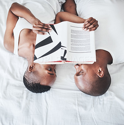 Buy stock photo Books, reading and overhead with a black couple in bed, lying together in the morning in their home. Read, book or love with a man and woman bonding in the bedroom of their house from above