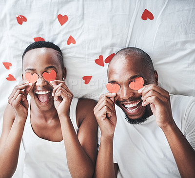 Buy stock photo Heart, bedroom and overhead with a valentines day black couple lying on a bed in their home together. Love, face or emoji with a romantic man and woman dating in their house to relax from above