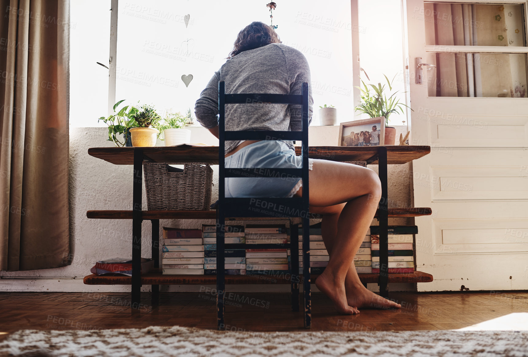 Buy stock photo Rearview shot of a young woman sitting at home