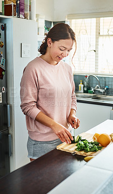Buy stock photo Cropped shot of a young woman chopping vegetables in the kitchen at home