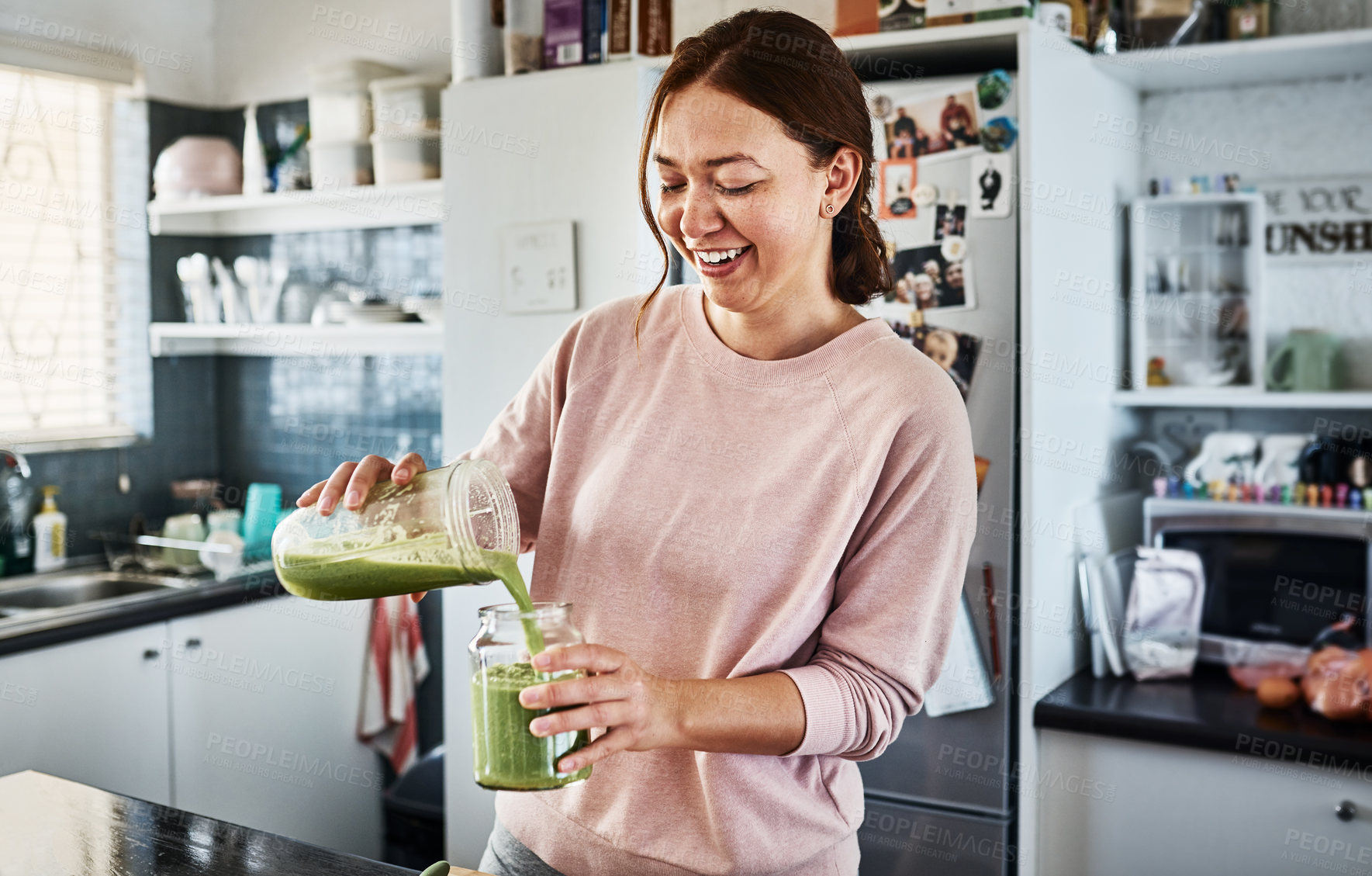 Buy stock photo Cropped shot of a young woman making a smoothie in the kitchen at home