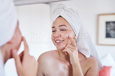 Buy stock photo Cropped shot of a beautiful young woman applying moisturizer to her face