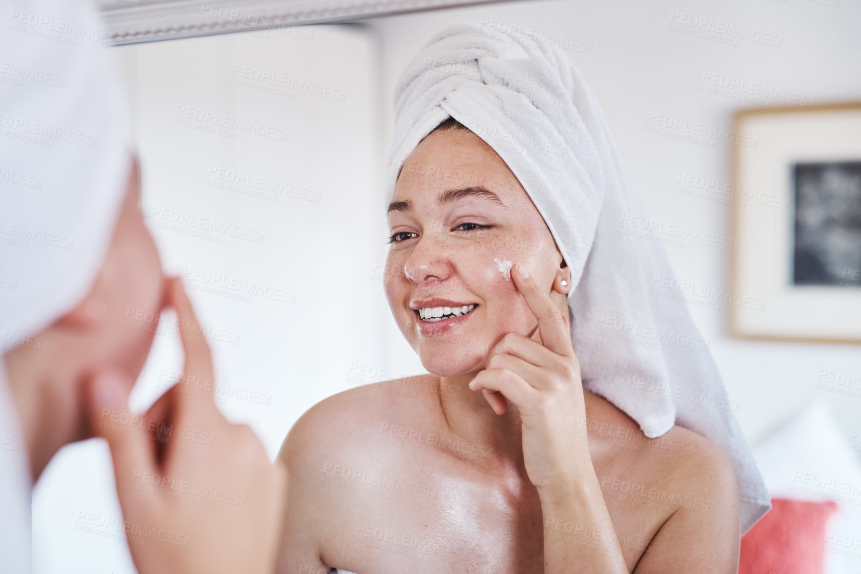 Buy stock photo Woman, mirror and face cream for cosmetics in bathroom with towel, smile and product for facial glow. Person, happy and reflection with serum, creme and routine with beauty, skincare and wellness