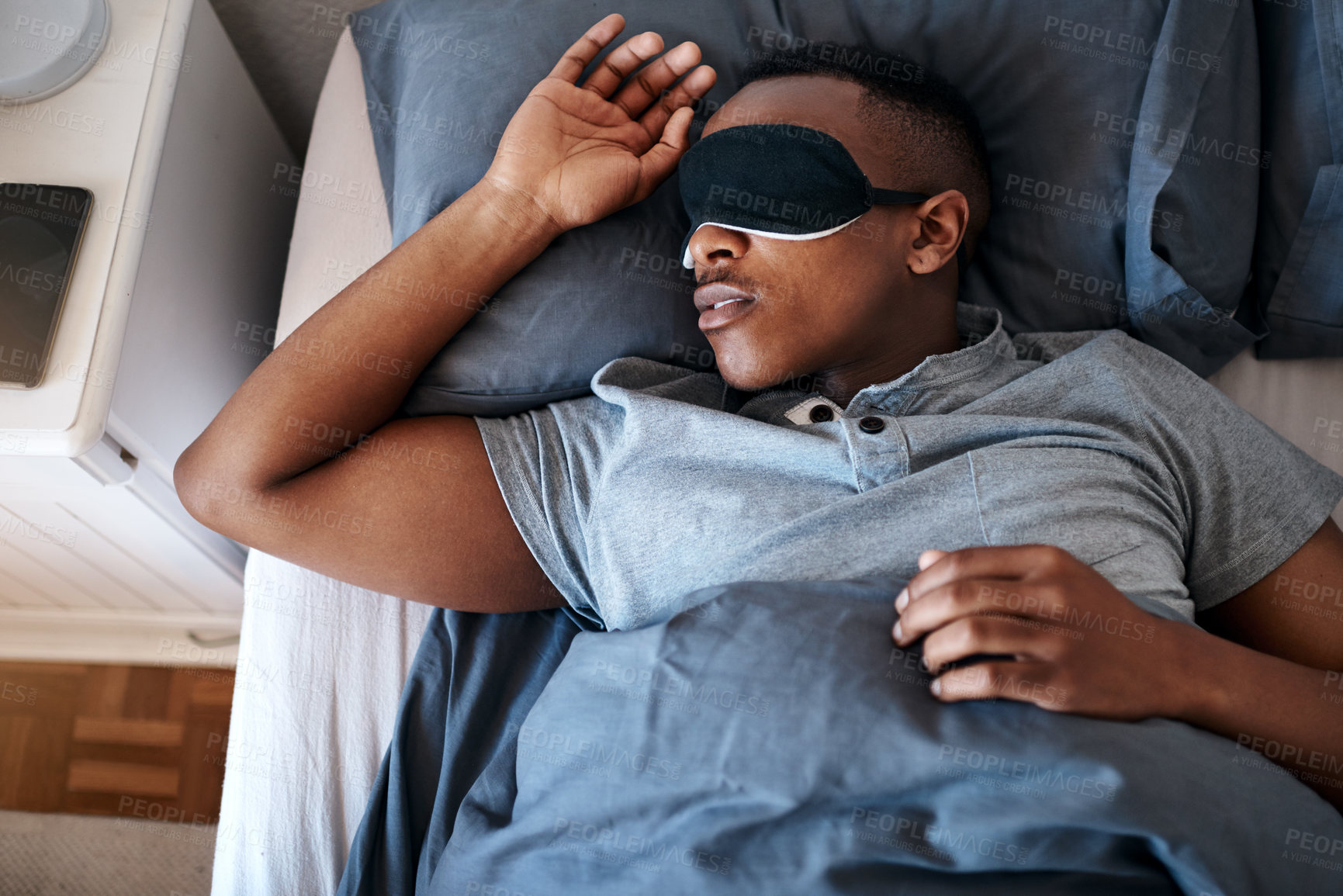 Buy stock photo Cropped shot of a handsome young man wearing a night mask and sleeping in his bed at home