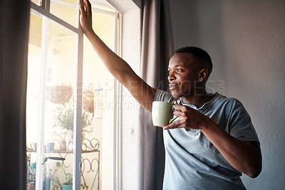 Buy stock photo Cropped shot of a handsome young man standing and looking contemplative in his bedroom while enjoying a cup of coffee