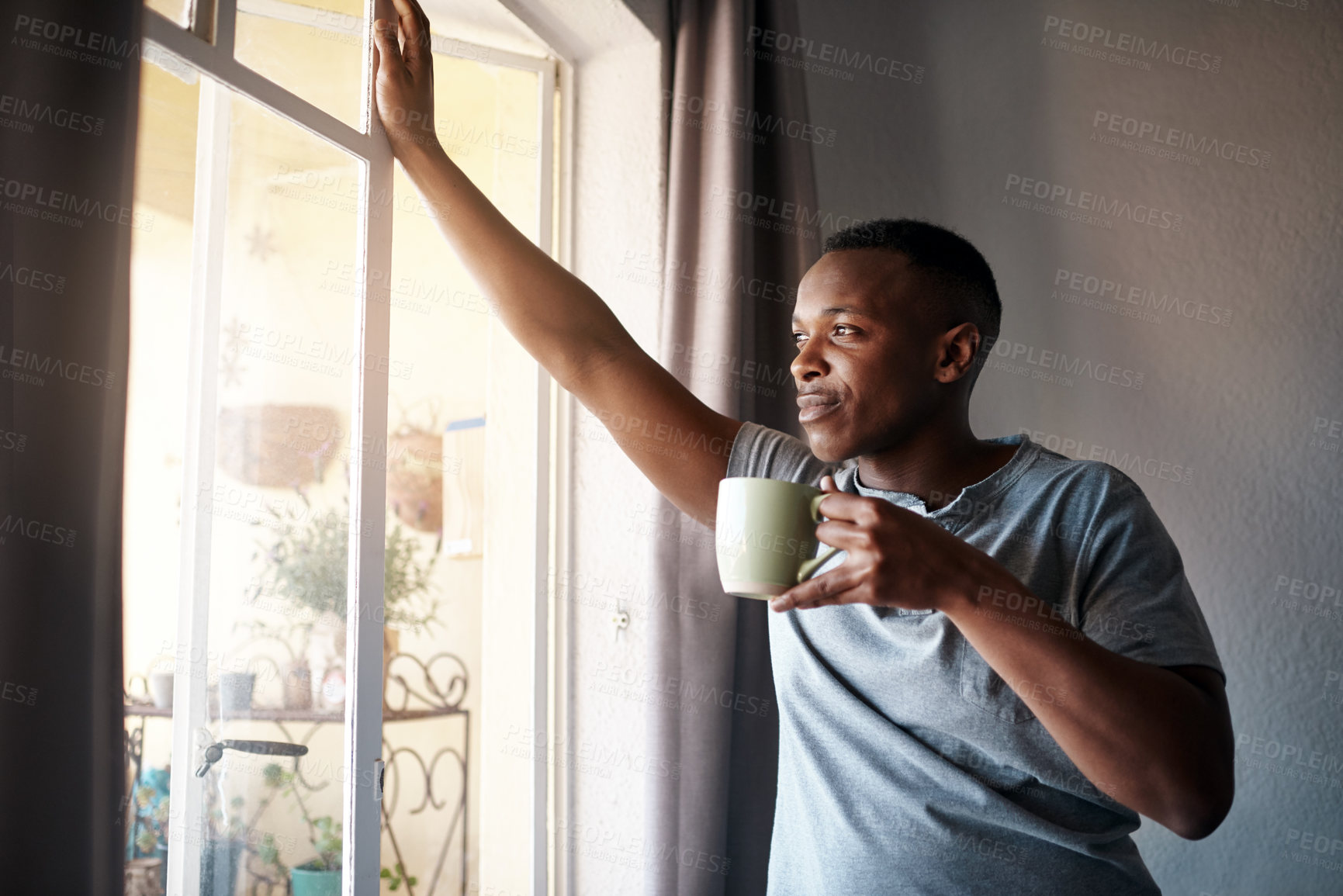 Buy stock photo Cropped shot of a handsome young man standing and looking contemplative in his bedroom while enjoying a cup of coffee