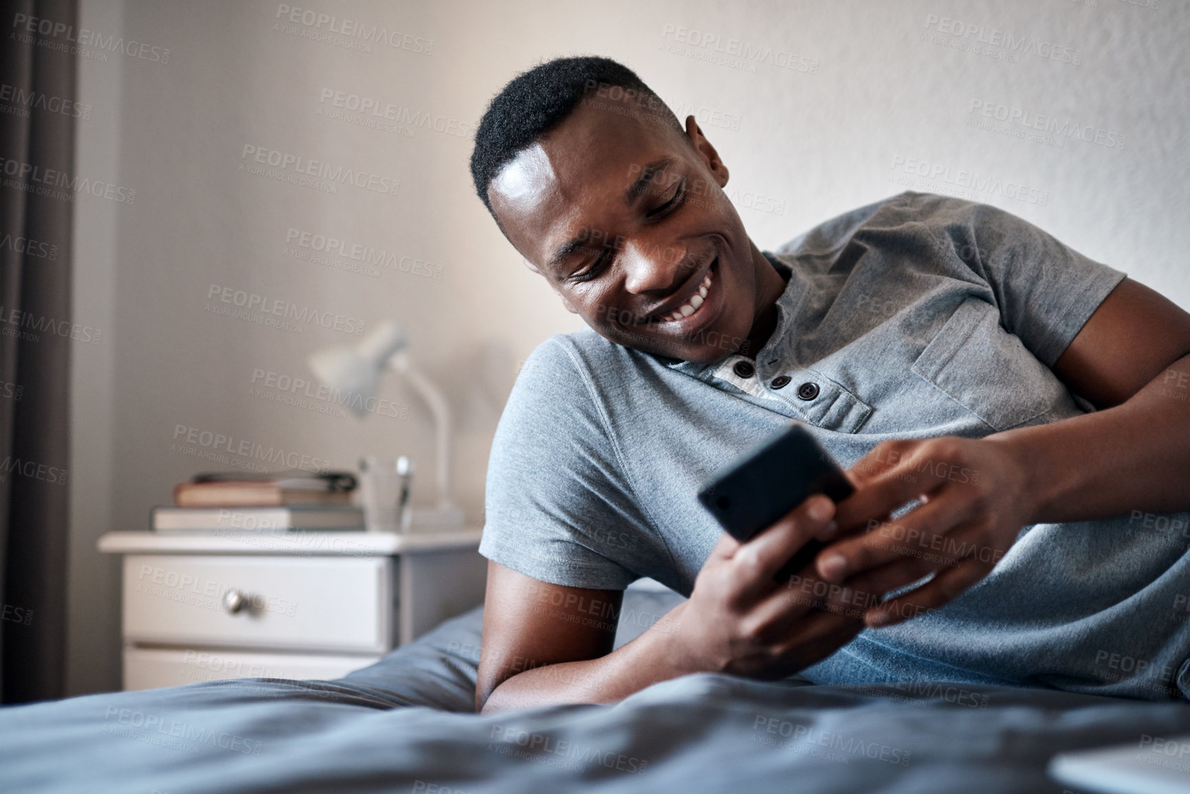 Buy stock photo Happy, morning and black man on bed with phone for social media, online chatting and internet in bedroom. Relax, rest and person on smartphone for website, networking and message on weekend in home