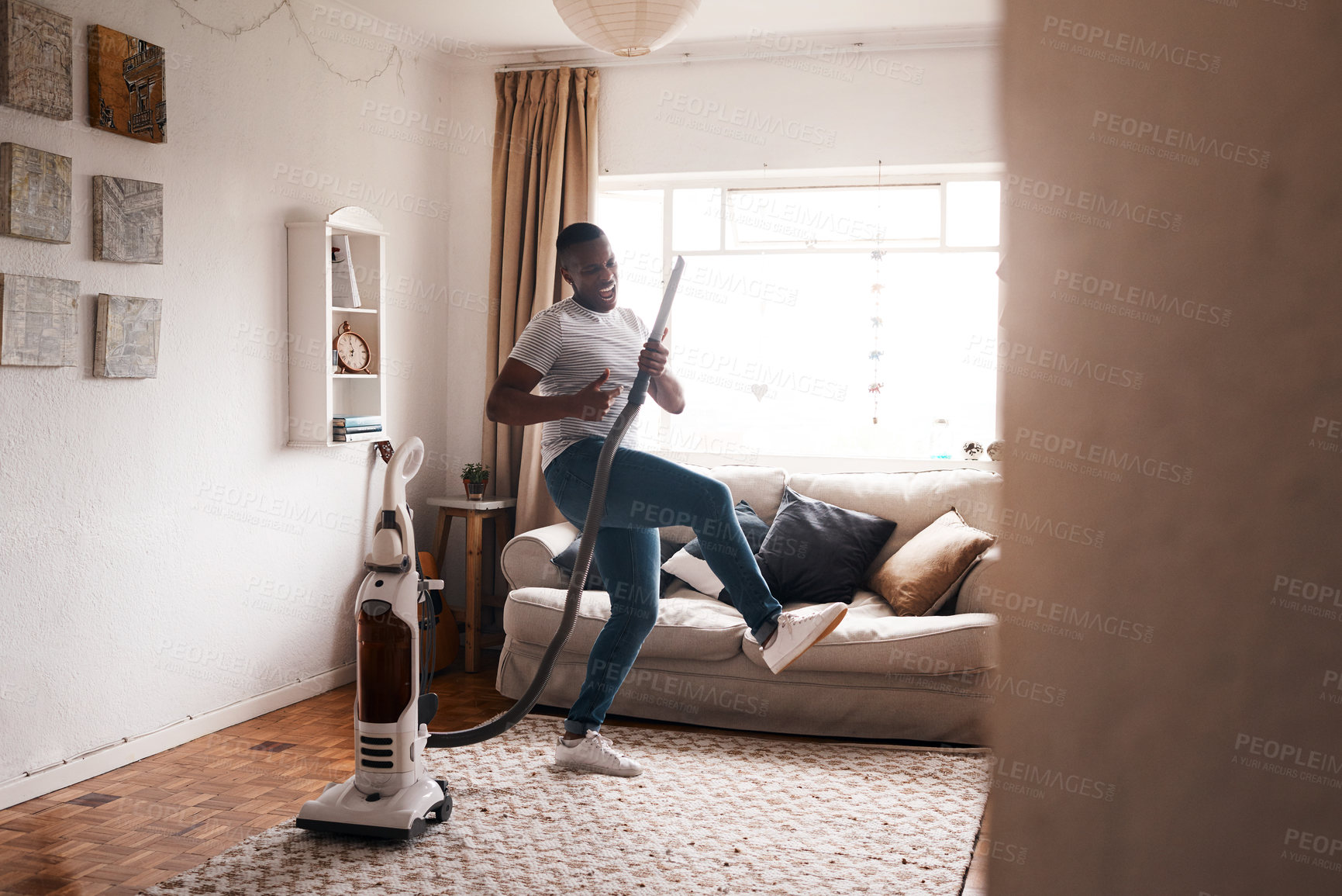 Buy stock photo Shot of a young man dancing while busy vacuuming the living room
