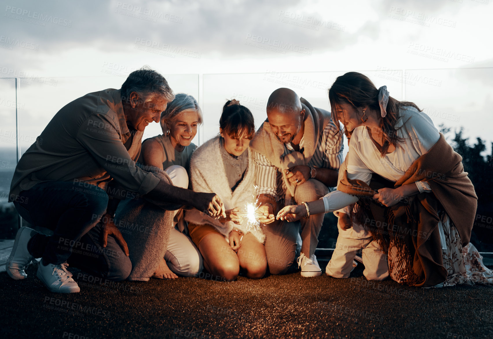 Buy stock photo Full length shot of an affectionate family lighting up sparklers while celebrating a new year outdoors