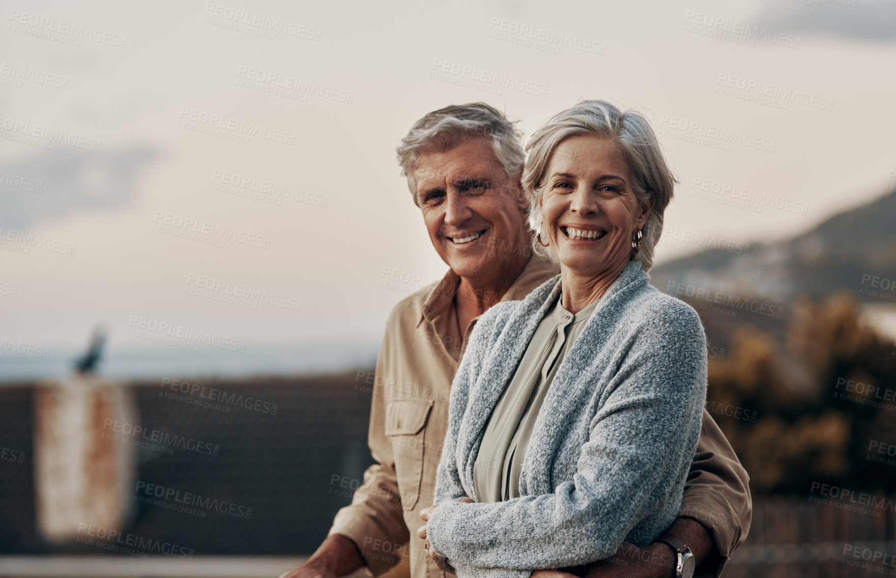 Buy stock photo Cropped portrait of an affectionate mature couple smiling while standing on a balcony outdoors