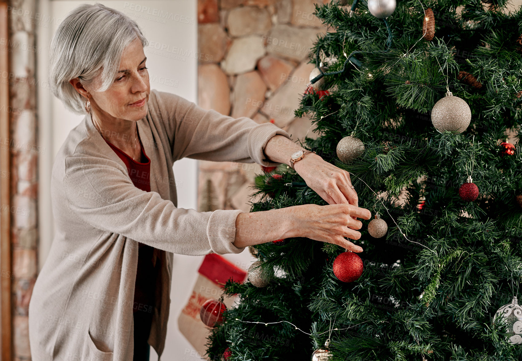 Buy stock photo Christmas, decoration and senior woman with a tree, celebration and hanging ornament in the living room. Festive, retirement and elderly person decorating a Christmas tree for the holiday in a home