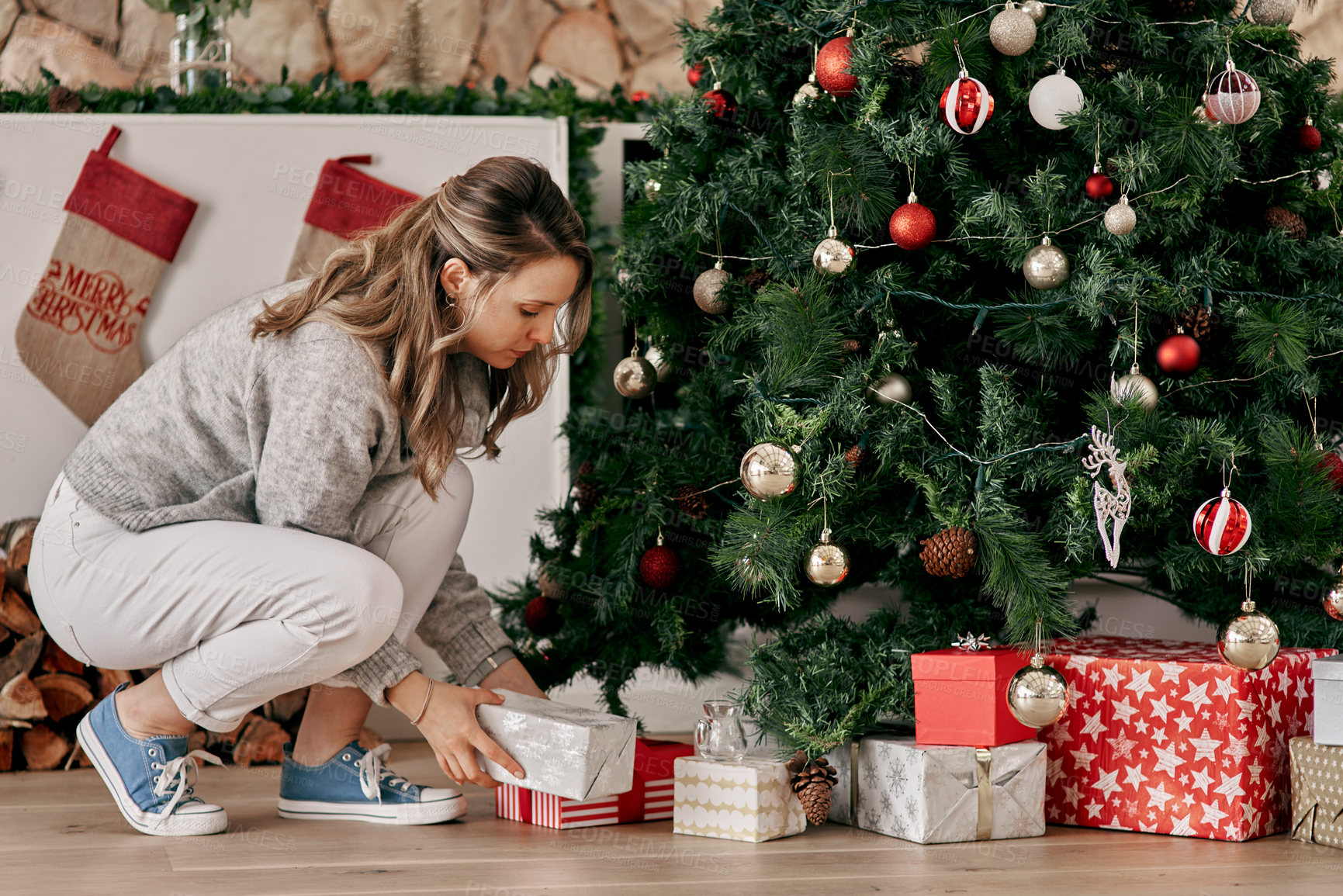 Buy stock photo Christmas, gift by tree and holiday celebration with woman, decoration, festive box and tradition at family home. Presents under the Christmas tree, celebrate and packing, ornament and creative.