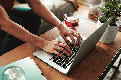 Buy stock photo Cropped shot of an unrecognizable woman using her laptop at home