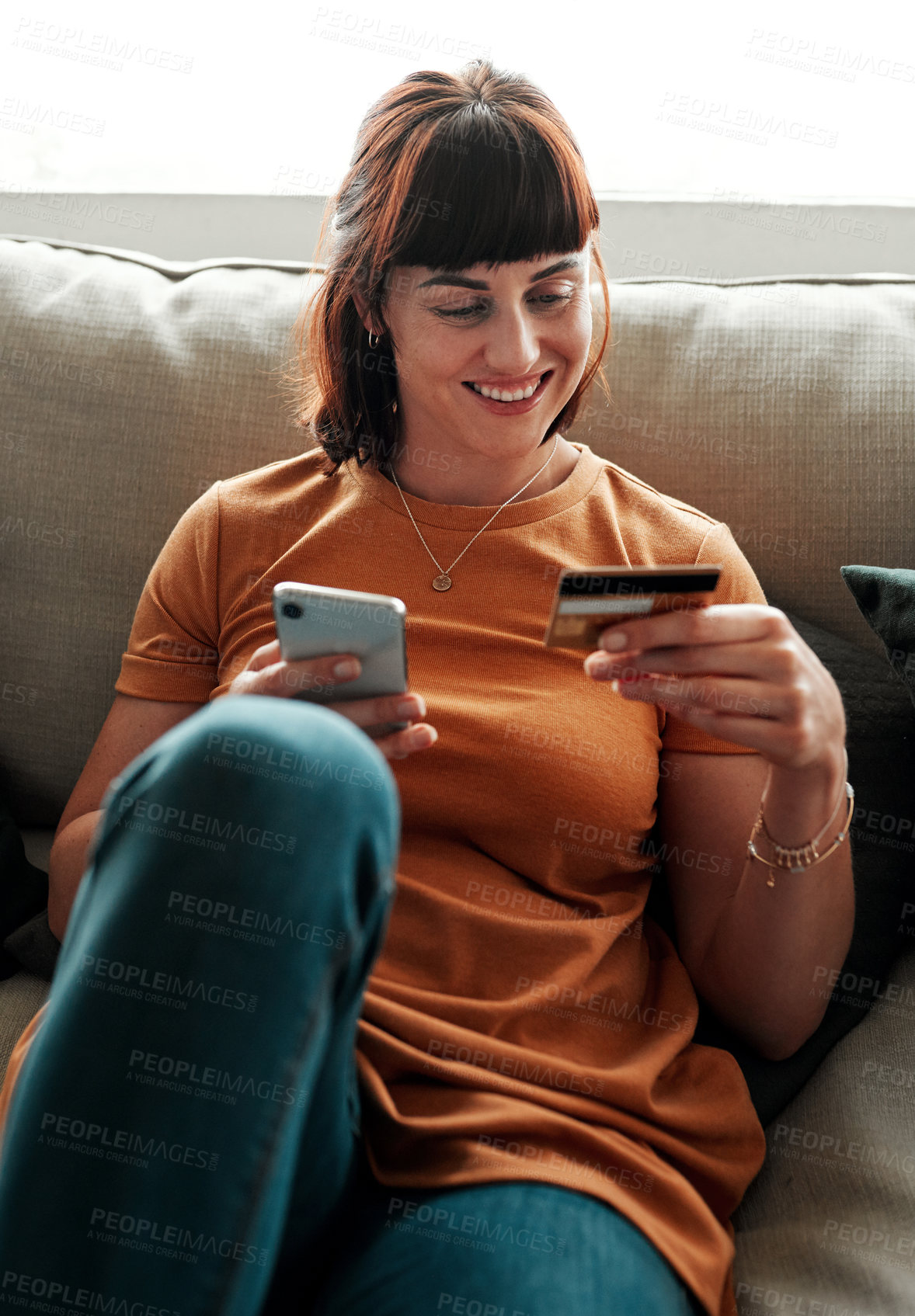 Buy stock photo Shot of a young woman holding her credit card while using her cellphone
