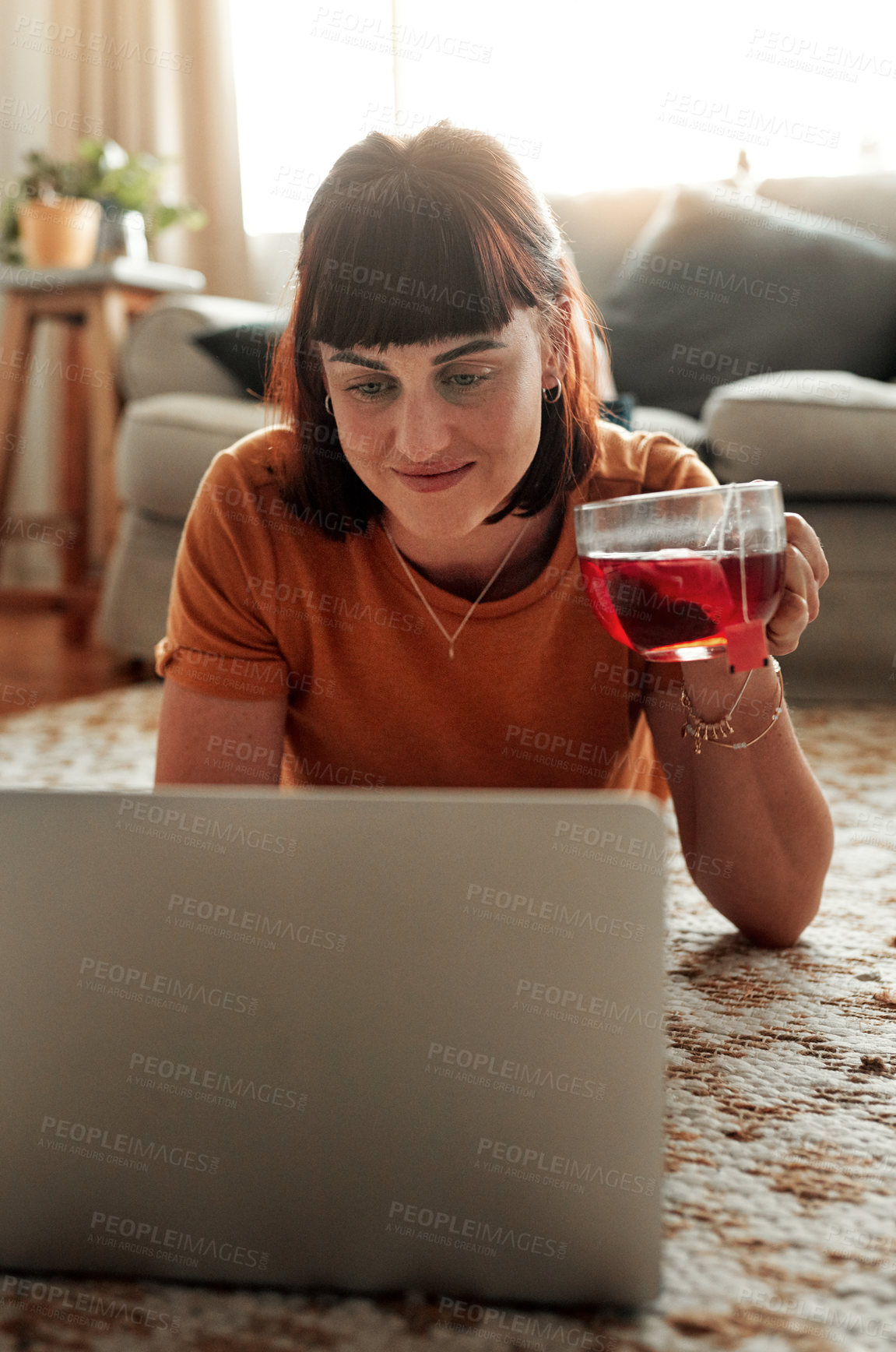 Buy stock photo Shot of a woman using her laptop while relaxing at home