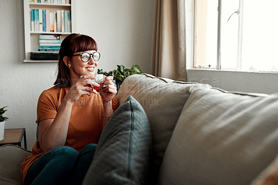 Buy stock photo Shot of a young woman enjoying a cup of tea while relaxing at home