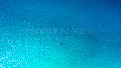 Buy stock photo Shot of a man and woman paddle boarding across the sea